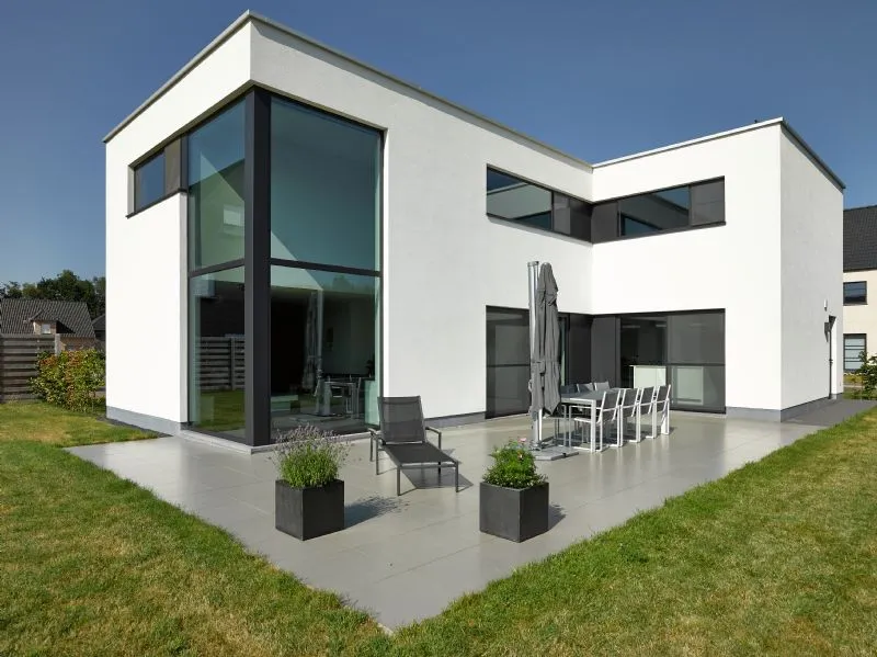 Witte woning met aluminium ramen over twee verdiepingen en een glazen hoek